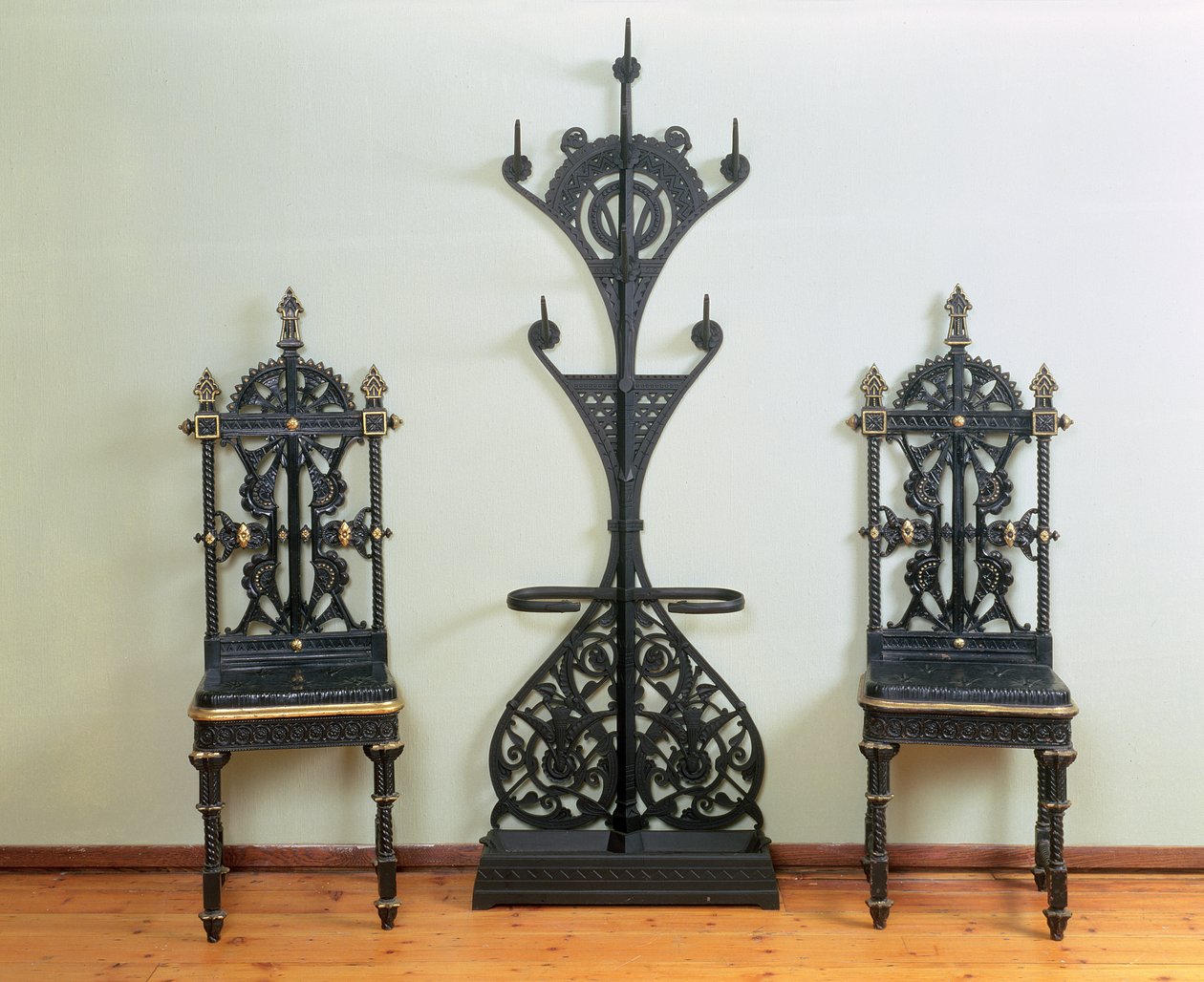 Brasão, chapéu e guarda-chuva estão flanqueados por duas cadeiras de jardim ou salão, Coalbrookdale, 1867-69 (ferro fundido) de Christopher Dresser