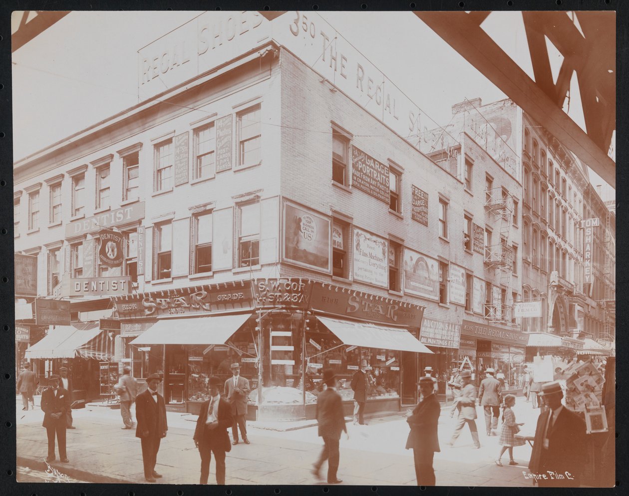 Esquina sudoeste da 14th Street e 3rd Avenue mostrando a loja Star Candies, um dentista, a loja Regal Shoe e a Empire Film Co. com pedestres, outdoors e uma viga da 3ª Avenida ferroviária elevada visível, c.1905 (foto a p/b) de Company Byron