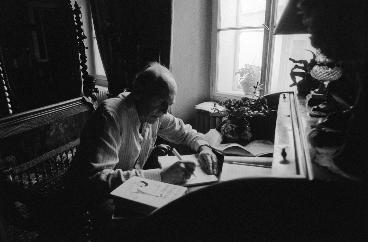 Jiri Mucha sentado em sua mesa em sua casa em Hradcany, Praga de Czech Photographer