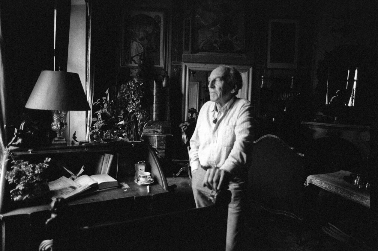 Jiri Mucha em pé ao lado de sua mesa em sua casa em Hradcany, Praga de Czech Photographer