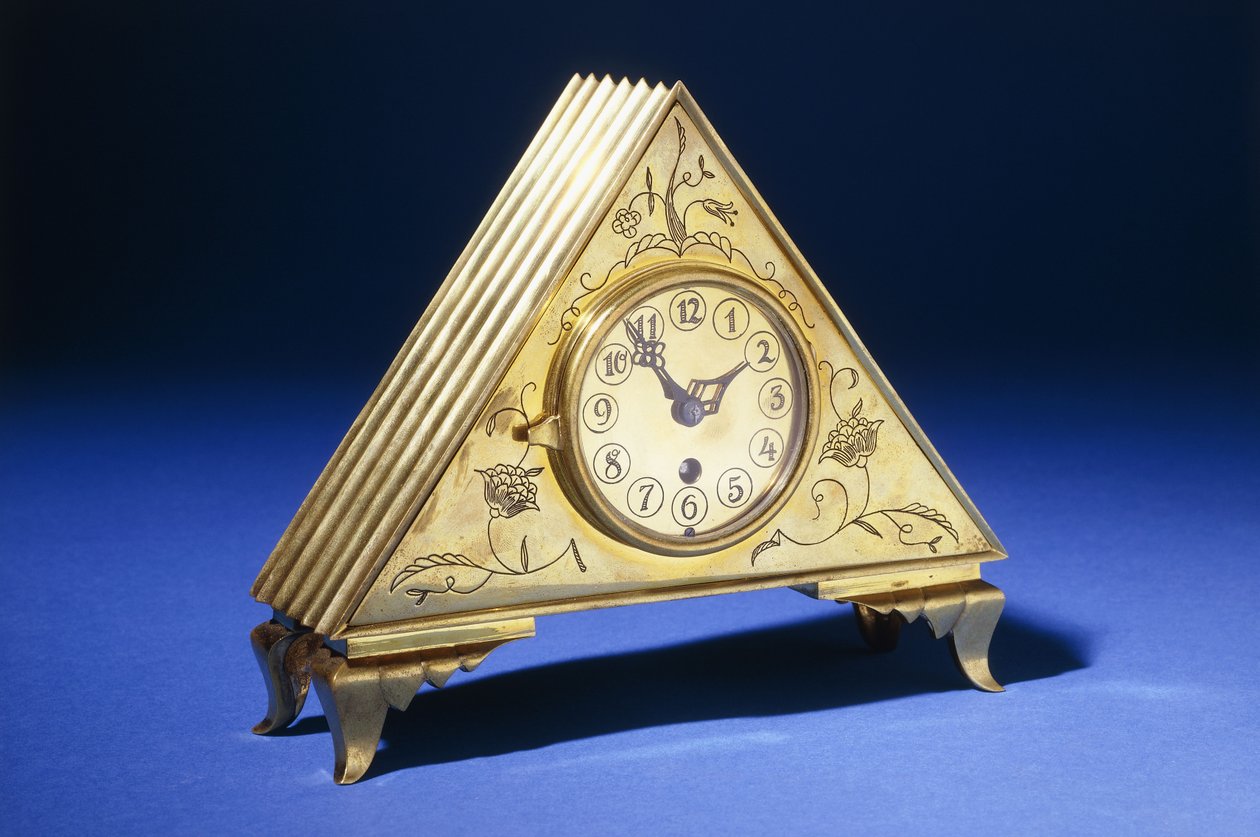 Um relógio de mesa triangular de latão com decoração floral gravada (latão) de Dagobert (attr. to) Peche