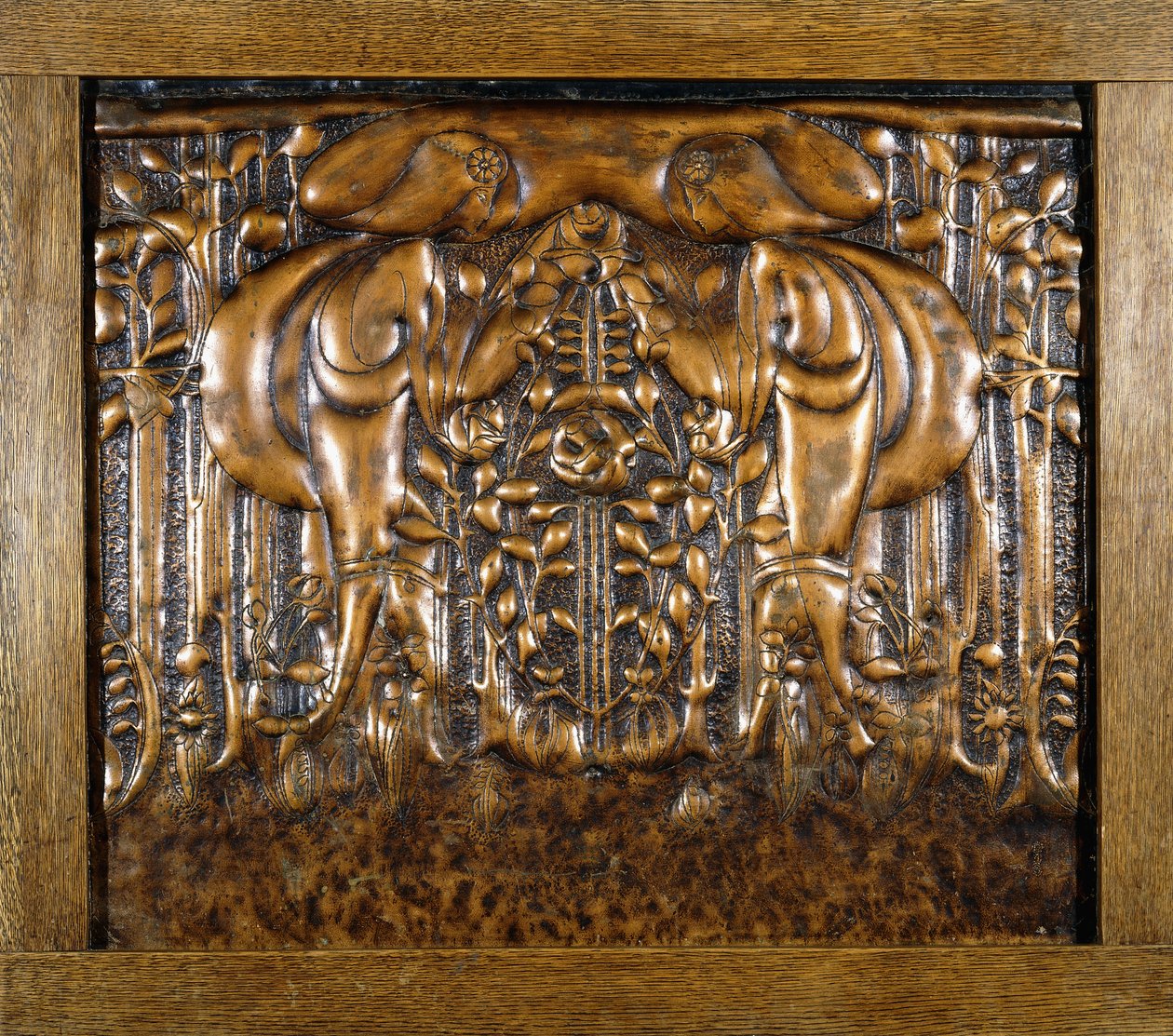 Um painel de chumbo decorativo moldado em alto relevo, retratando duas donzelas estilizadas em frente de Donald McKay Stoddart