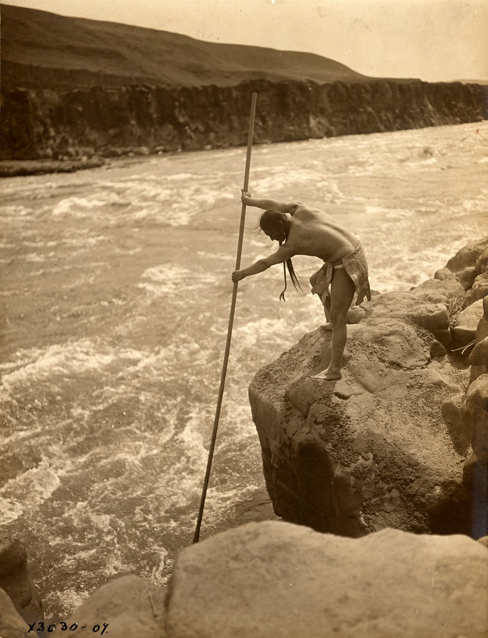Índio Tlakluit, de pé sobre uma rocha, a pescar com rede de mergulho, c.1910 (fotografia a preto e branco) de Edward Sheriff Curtis