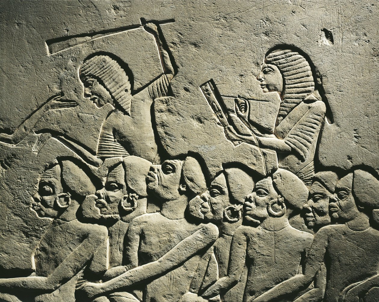 Um grupo de prisioneiros negróides rodeados por guardas armados com bastões enquanto um escriba redige um relatório. Relevo do túmulo de Horemheb em Saqqara, pormenor de Egyptian 18th Dynasty