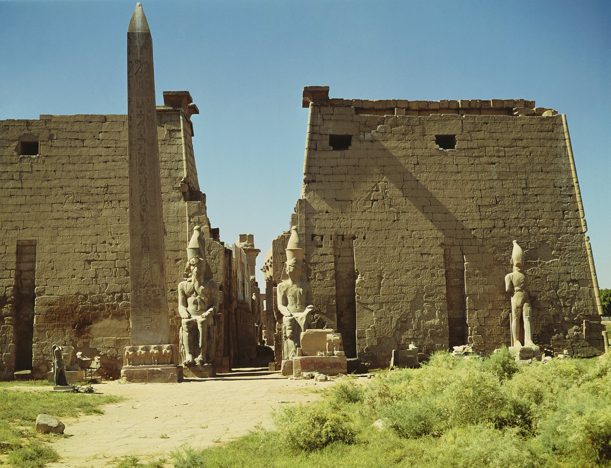 Fachada e Primeiro Pilar com duas estátuas sentadas de Ramsés II e o restante do obelisco de Egyptian 19th Dynasty