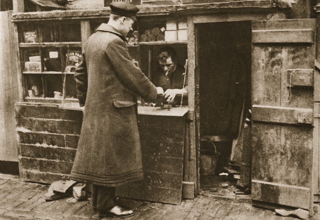 Um sapateiro, estabelecido em um estande improvisado em uma calçada de Mayfair, recebe botas de um chofer, da revista Wonderful London, publicado em 1926-27 (fotogravura) de English Photographer