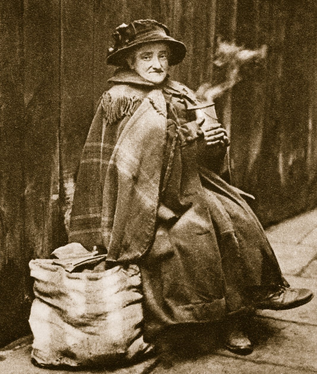 Uma senhora da rua que bebe o chá de uma lata de cerveja típica de East End, perto da rua de Fleet (foto do sepia) de English Photographer