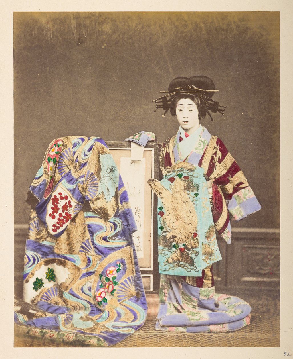 mulher japonesa em traje tradicional, ] 
Retrato em estúdio de pé de uma mulher com um traje e penteado elaborados, com outro manto drapeado sobre a moldura ao seu lado, Fotógrafo: Colecção Lucas Desconhecida: Registo fotográfico da w de English Photographer
