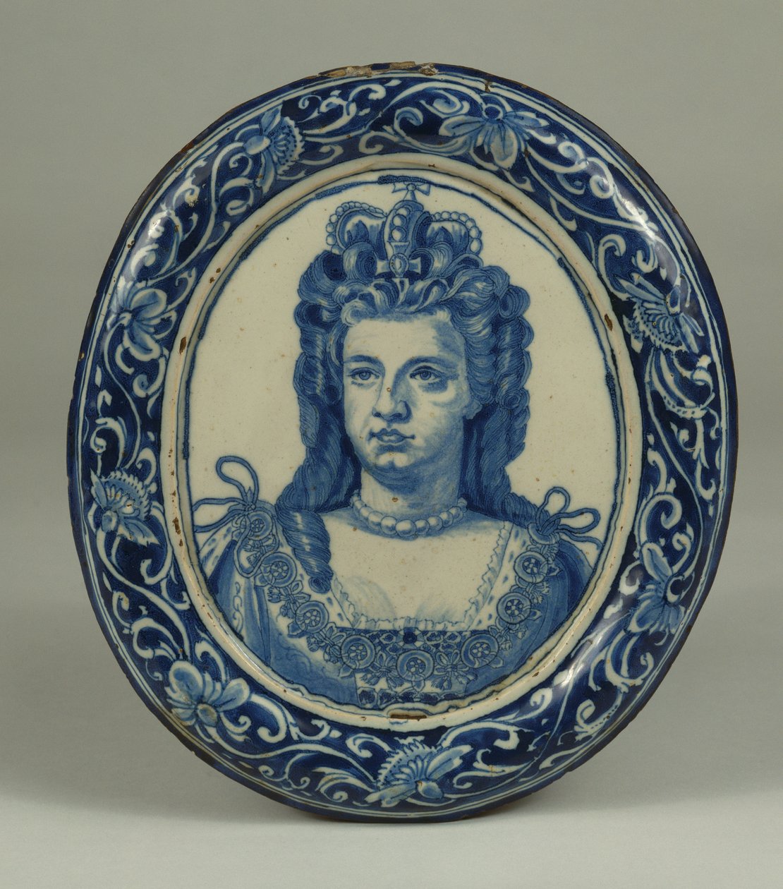 Uma placa de retrato real oval Delft em azul e branco da Rainha Anne, provavelmente Londres, c.1705 de English School