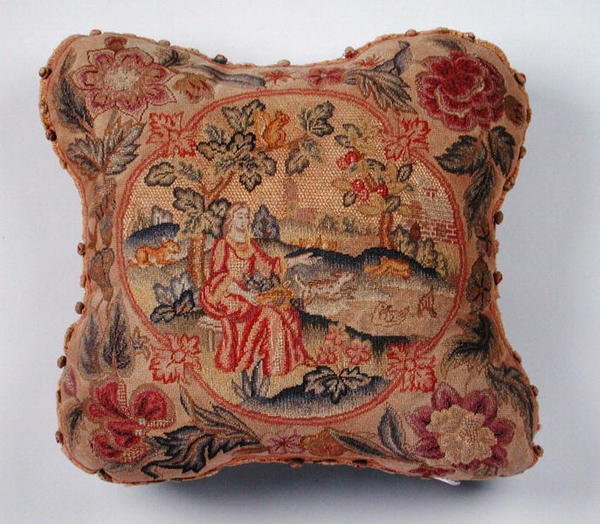 Almofada, bordada em petit point, retratando uma mulher numa paisagem (têxtil) de English School