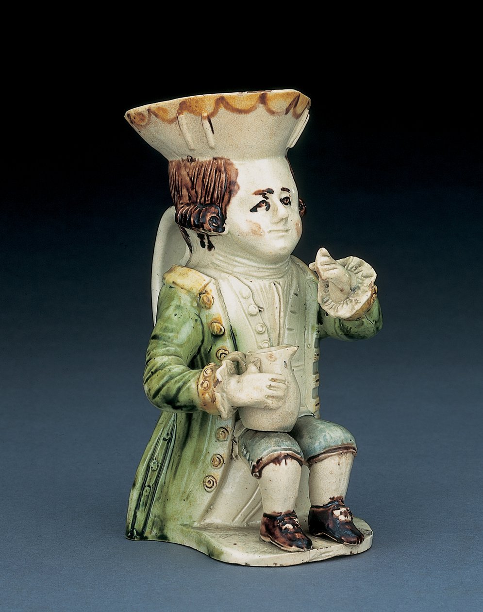 Jarro Toper toby, seu chapéu com borda recortada marrom e amarela, seu cabelo castanho incisado em fila e com uma roseta branca assentada com um jarro de balaústre no joelho, c.1770 de English School
