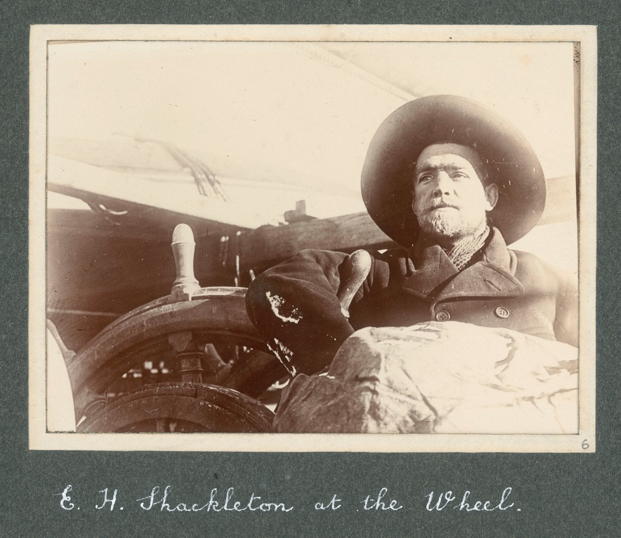 E H Shackleton de pé junto à roda do "Discovery" (1901) Do álbum de Sir Ernest Henry Shackleton intitulado National Antarctic Expedition (1901-1903) de Ernest Henry Shackleton