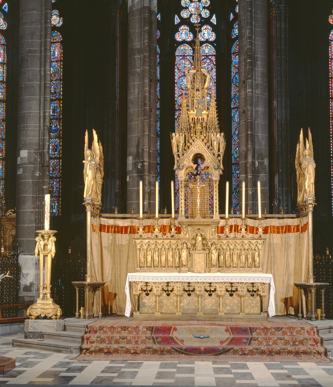 Altar alto em estilo neo-gótico, rodeado de quatro anjos carregando os instrumentos da Paixão de Cristo com um tabernáculo encimado por um pináculo elaboradamente decorado de Eugene Emmanuel Viollet le Duc