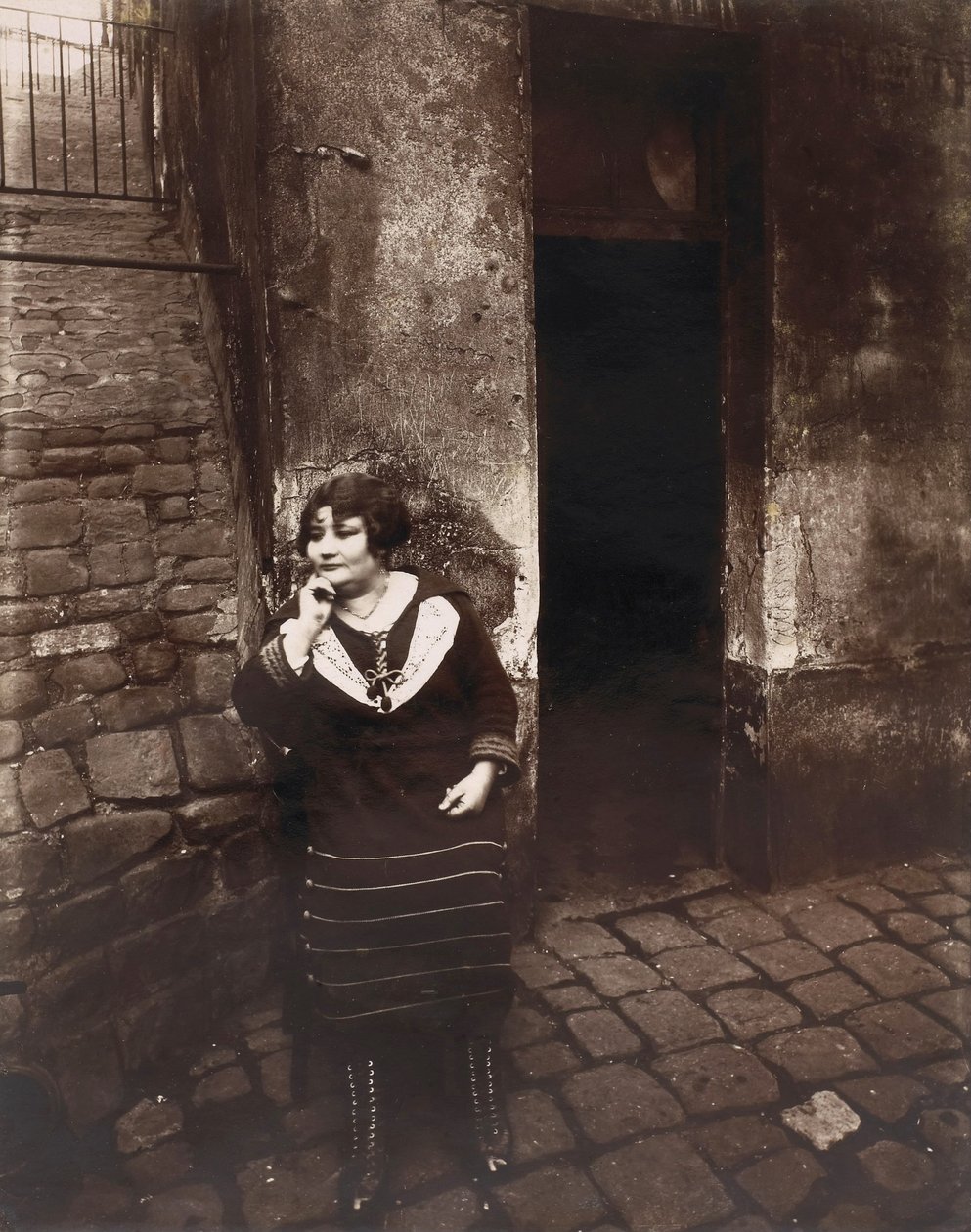 La Villette. Rue Asselin, prostituta esperando na frente de sua porta de Eugène Atget