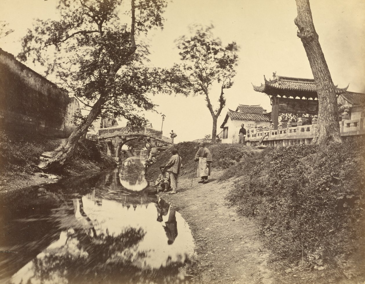 [Vista chinesa de um rio e de uma ponte numa aldeia com vários chineses]. de Felice Beato