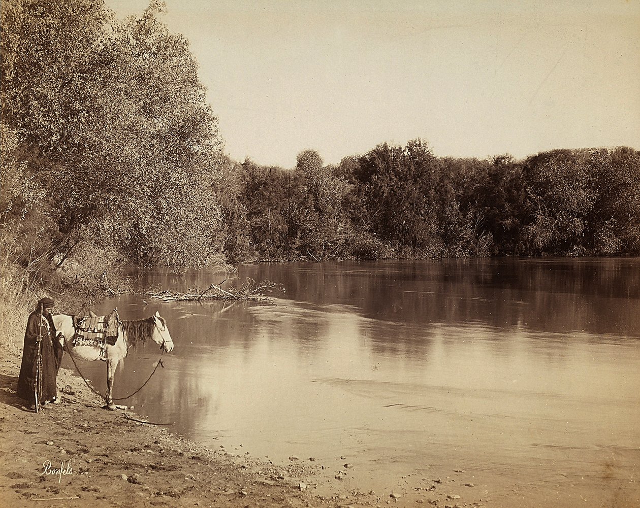 Um homem de vestido tradicional com o seu cavalo, em frente a um lago no Egipto. de Félix Bonfils