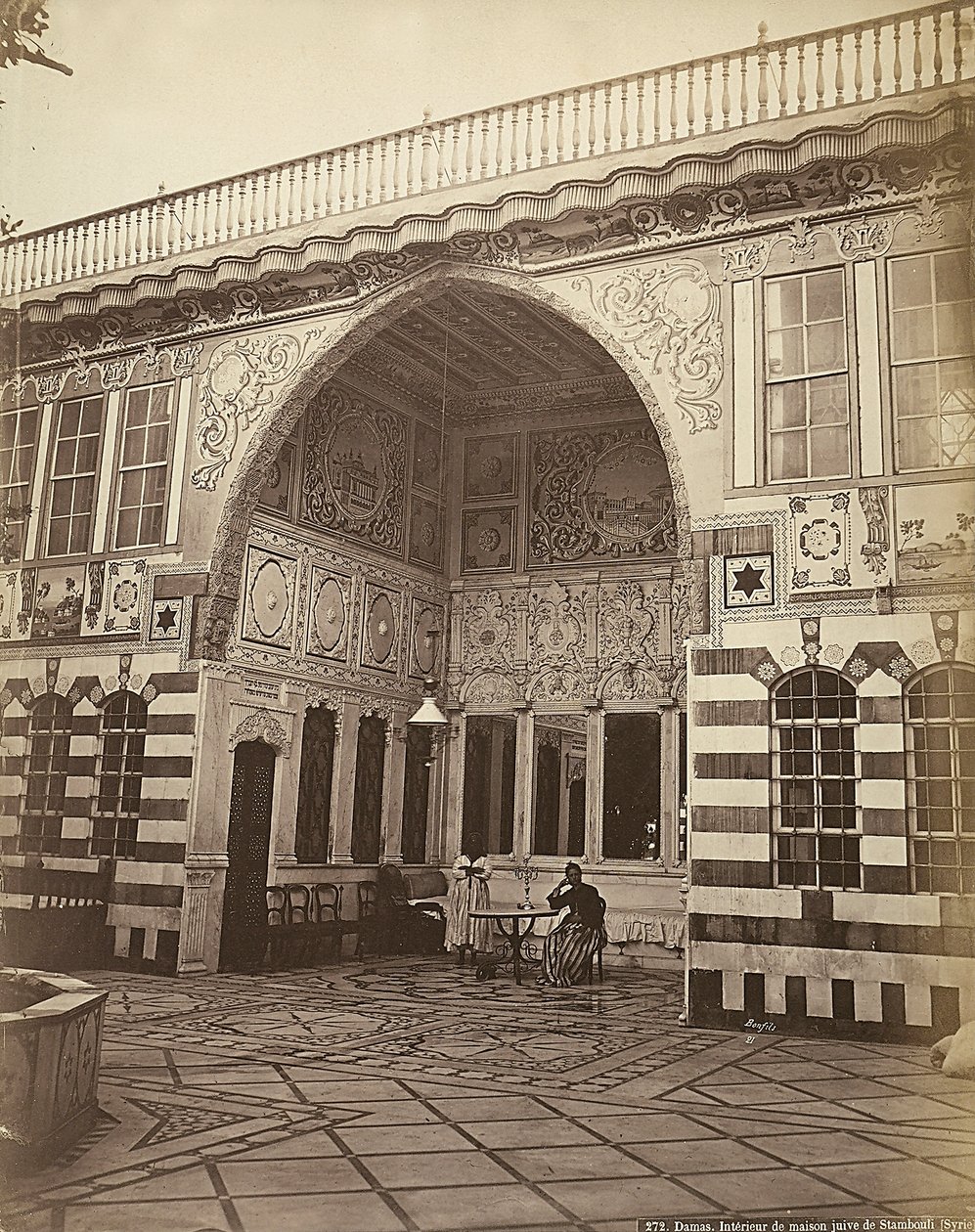 Interior de uma casa judaica em Stambouli, na Síria. Duas mulheres são mostradas debaixo de um pórtico. de Félix Bonfils