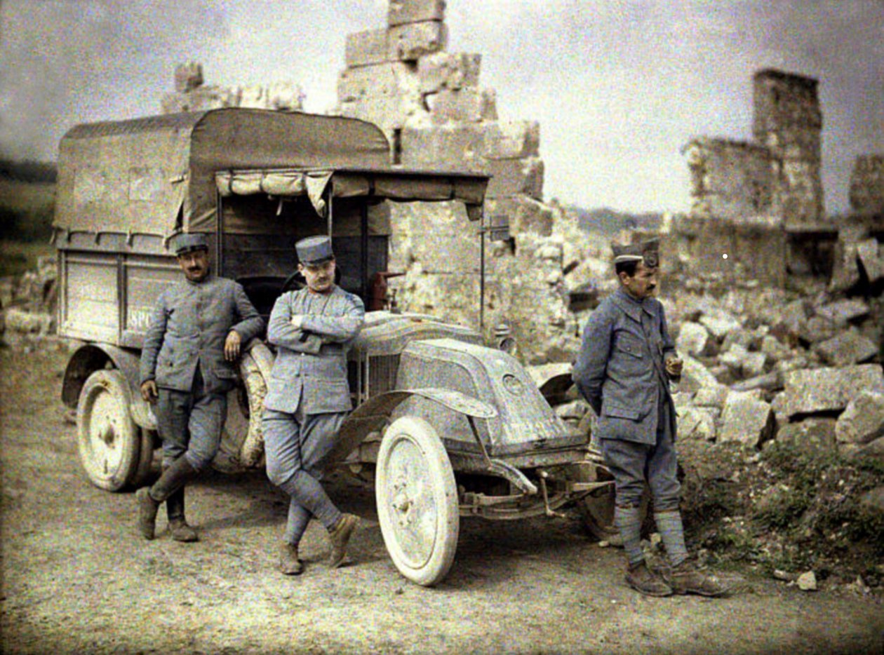 Três soldados franceses estacionaram em frente a um edifício fortemente danificado com um pequeno caminhão, Aisne, França, 1917 (autocrômico) de Fernand Cuville