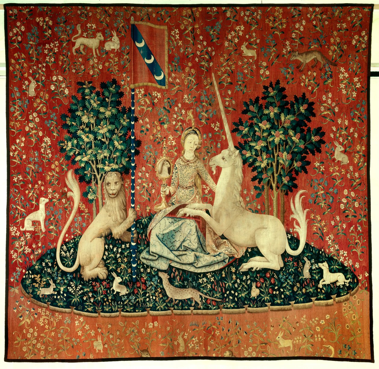 Cortina da Senhora do Unicórnio: a vista. Uma jovem mulher segurando um espelho rodeada por um leão, um unicórnio, um macaco, coelhos. Tapeçaria de lã e seda feita entre 1484 e 1500. Do Chateau de Boussac, Creuse. Dim. 3,7x4,7 m. P de Flemish School