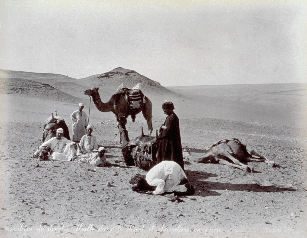 Cameleiros egípcios durante uma pausa no deserto. Em primeiro plano, dois membros do pequeno grupo parecem estar rezando de Félix Bonfils