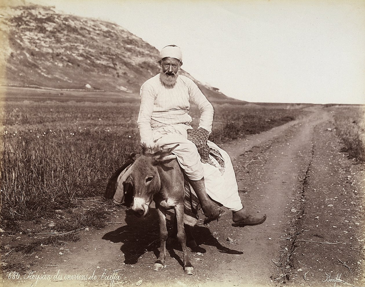 Retrato de um camponês de perto de Haifa. O homem está montando um burro. de Félix Bonfils