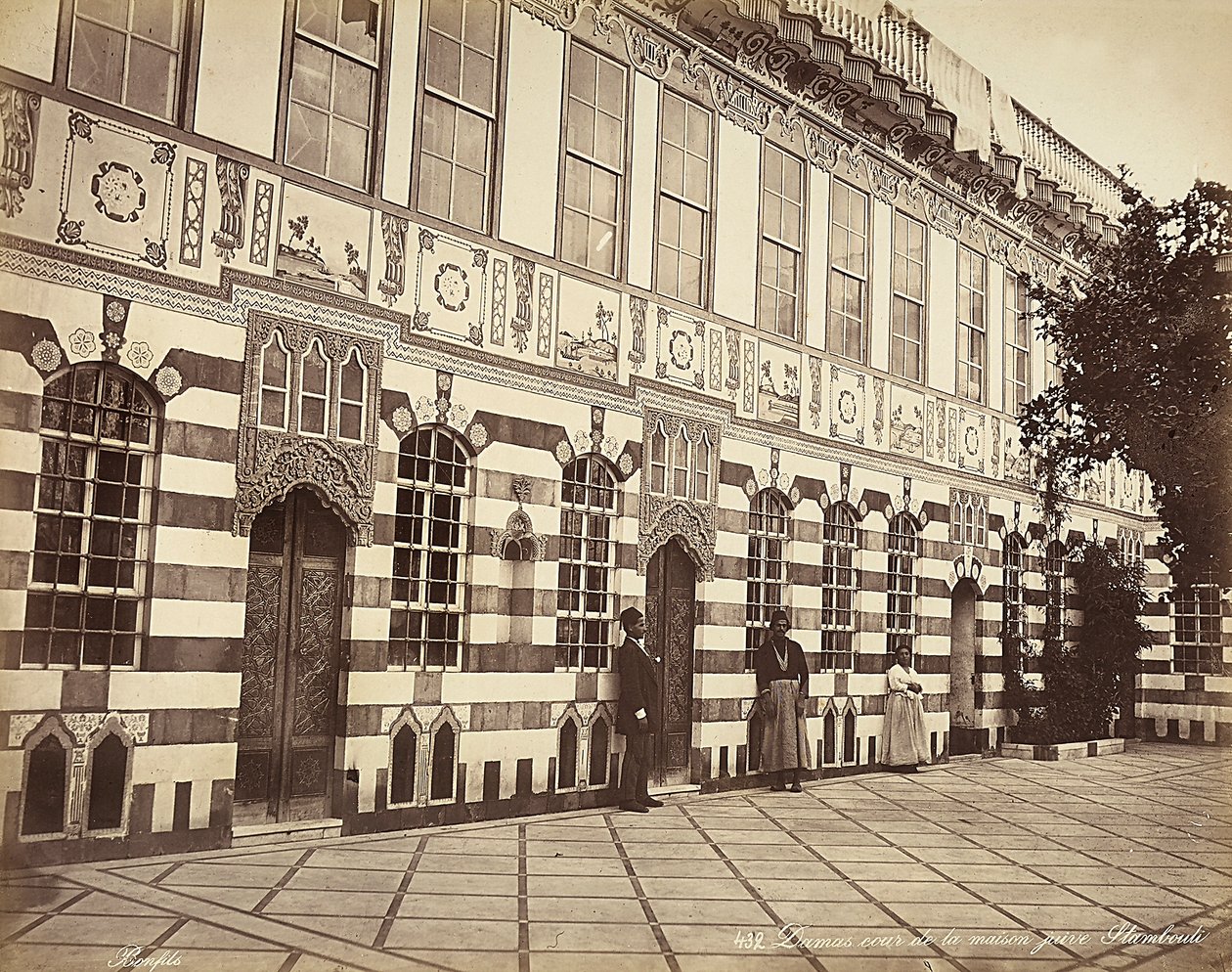 O pátio de uma casa judaica em Stambouli, na Síria, Três domésticos são mostrados perto das paredes do edifício de Félix Bonfils