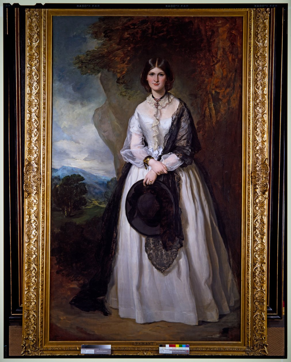 Retrato de uma senhora de vestido branco, de pé, numa paisagem de Francis Grant