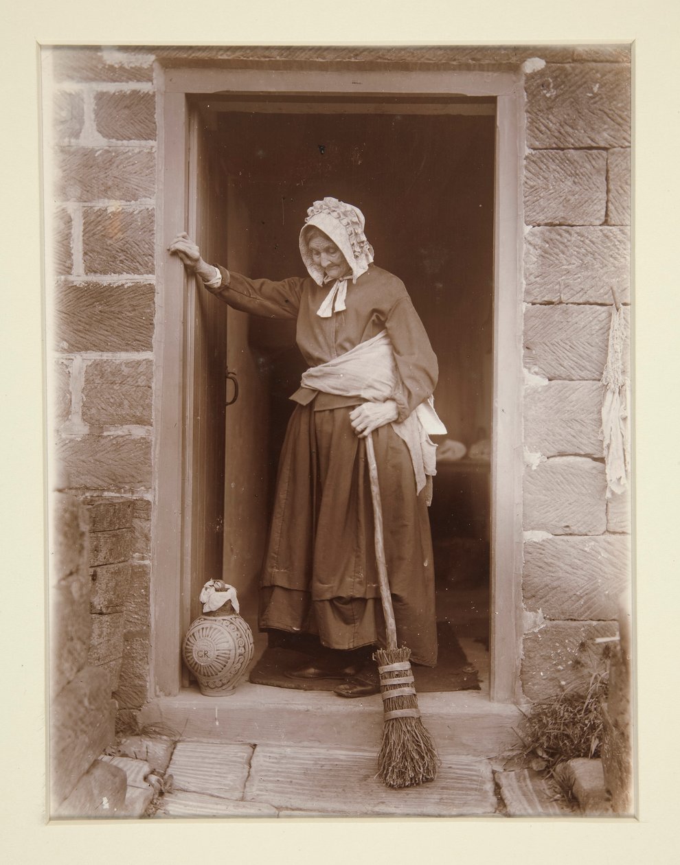 Uma velha senhora com uma garrafa de levedura na porta de uma casa de campo de Frank Meadow Sutcliffe