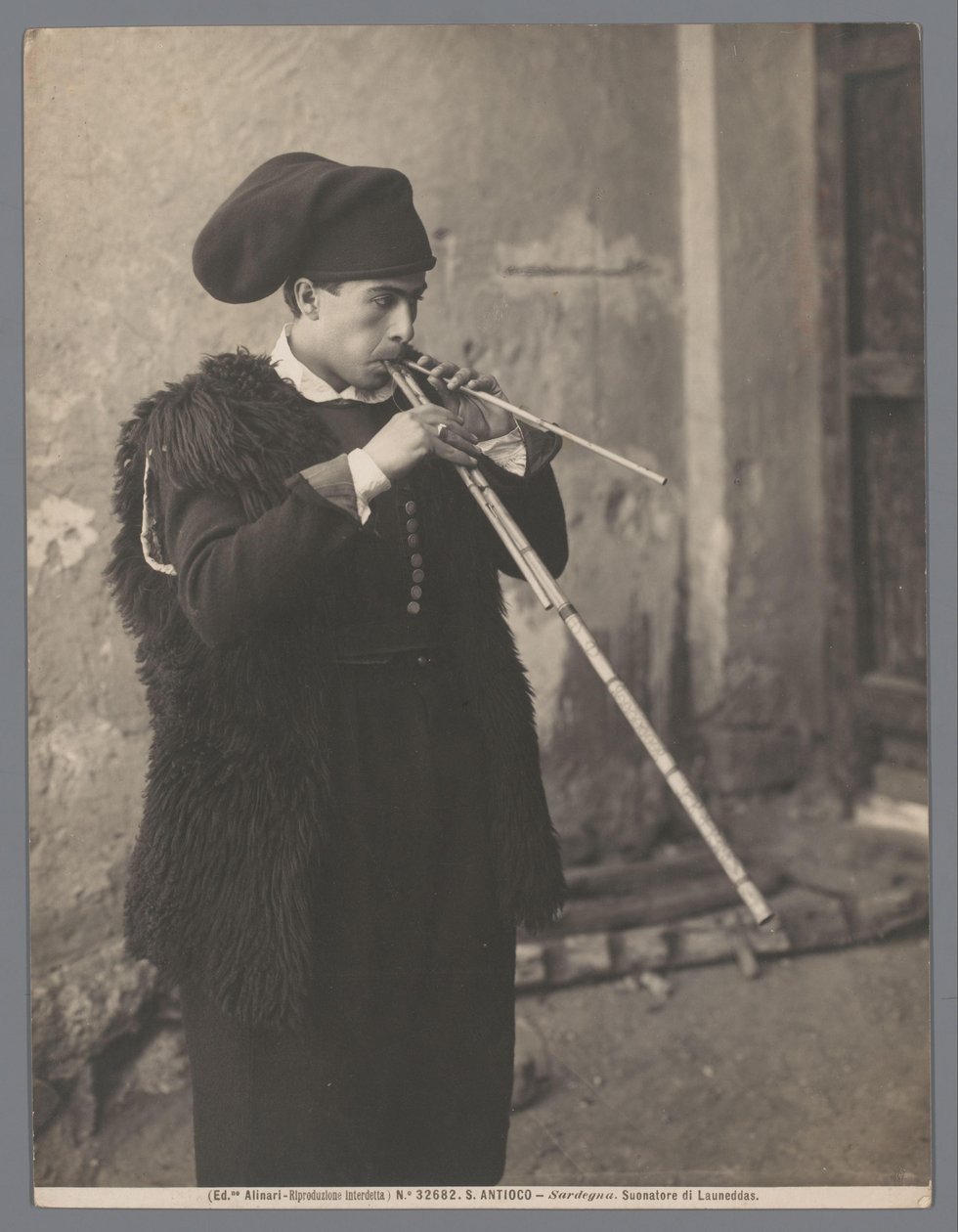 Flautista com capacete Suonatore di Launeddas (título no objeto) S. Antioco-Sardegna (título da série no objeto) de Fratelli Alinari