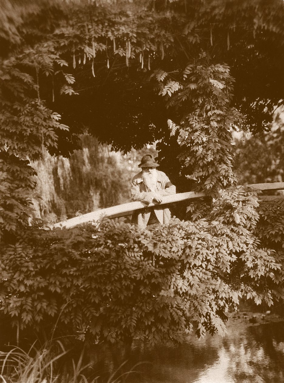 Claude Monet na ponte japonesa em seu jardim em Giverny, c.1920 de French Photographer
