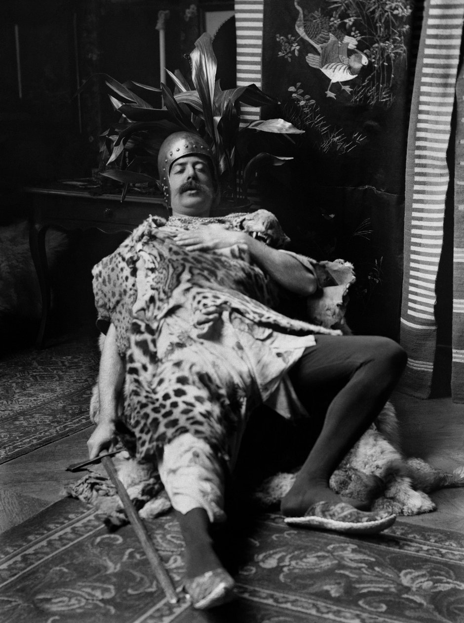 Um homem vestido de peles de tigre, capacete e um espadachim na mão, mesmo teatralmente a morte do guerreiro, na Abadia de Septfontaines, perto de Bourmont en Haute Marne. Fotografia de finais do século XIX. Coleção Ducos. de French Photographer