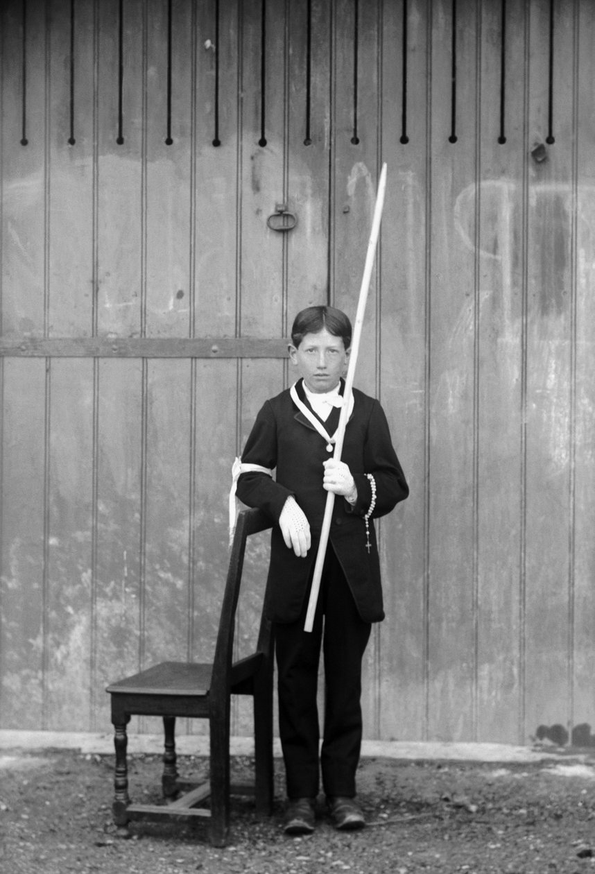Primeiro comunicante, vestido de branco e luvas, com medalhas, rosário, punho de renda branco e usando uma vela muito comprida, perto de Bourmont em Haute-Marne (Haute Marne), por volta de 1880. Fotografia. Coleção Ducos. de French Photographer