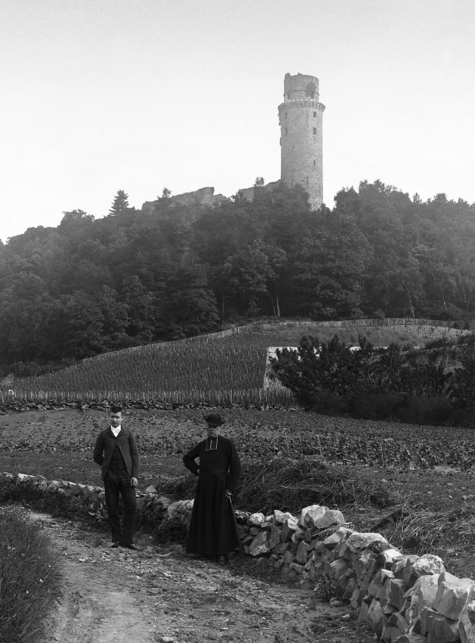 A cura do campo, acompanhada por um jovem, posando no caminho em frente à torre de Montlhery, no Essone. Fotografia de finais do século XIX. Coleção Ducos. de French Photographer