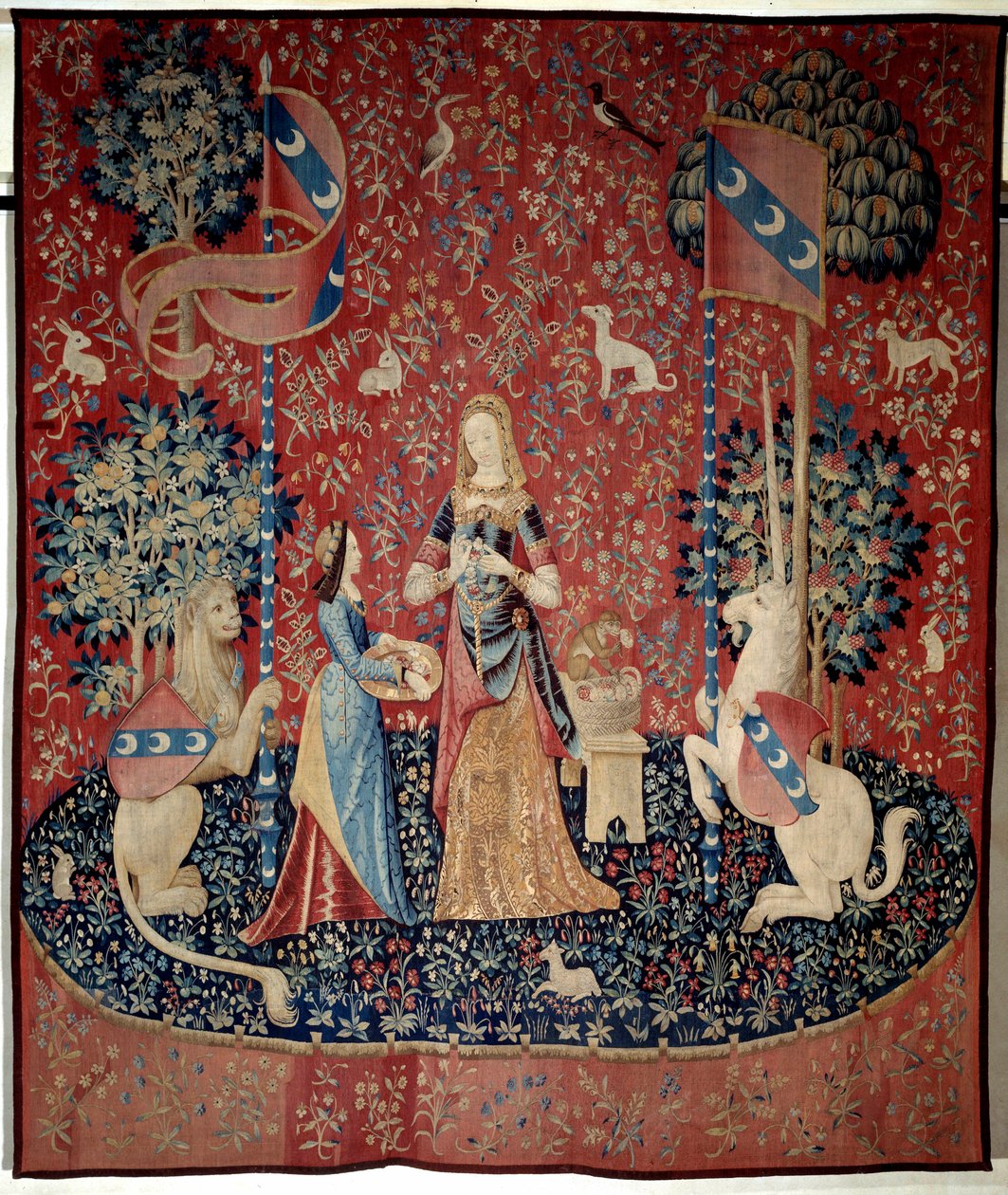 Cortina da Senhora para o Unicórnio: alegoria do olfato. Uma jovem mulher segurando uma coroa de cravos, rodeada por um leão, um unicórnio, um macaco, coelhos. Tapeçaria de lã e seda, feita entre 1484 e 1500. Do Chateau de Boussac, Cr de French School