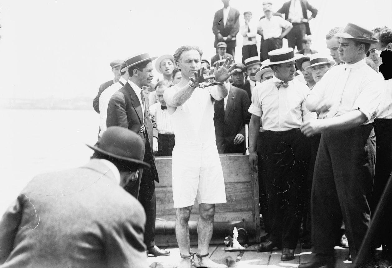 Harry Houdini sendo algemado antes de ser pregado em uma caixa e abaixado na Baía de Nova York, 1912 de George Grantham Bain