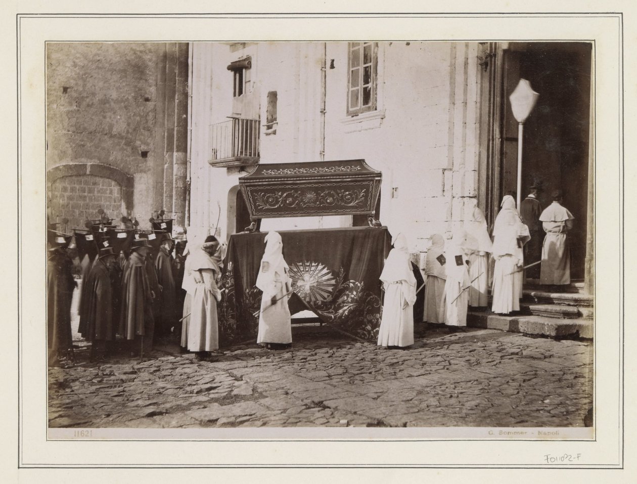 Cortejo fúnebre de monges com capuzes pontiagudos à entrada de uma igreja em Itália de Giorgio Sommer