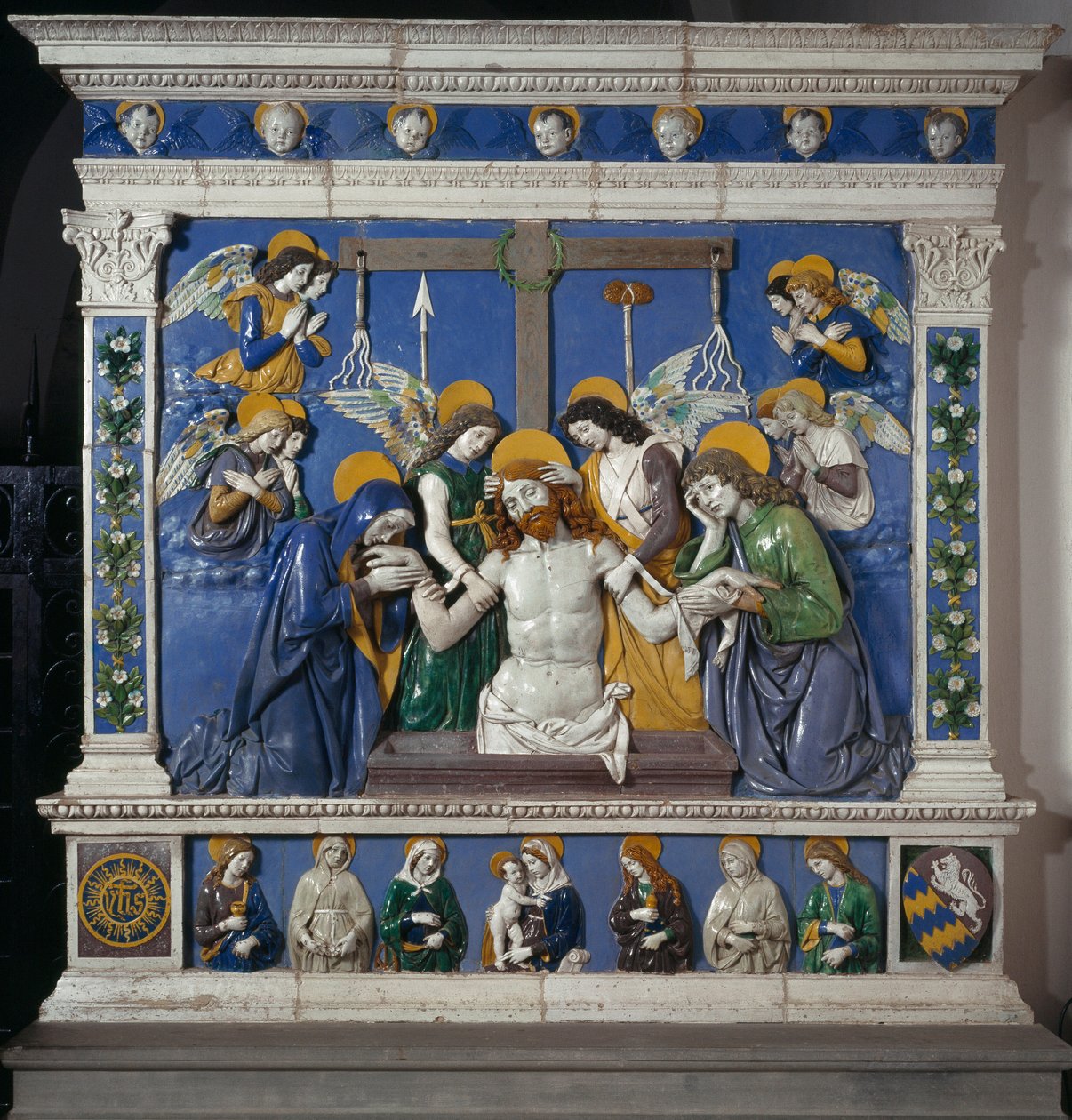 O Depósito de Jesus no Santo Sepulcro com a Virgem e São João Evangelista Representação dos símbolos da Paixão: chicotes, coroa de espinhos e esponja embebida em vinagre (posca). Cerâmica em alto relevo de Giovanni della Robbia (1469-1529), cerca de 14 de Giovanni della Robbia