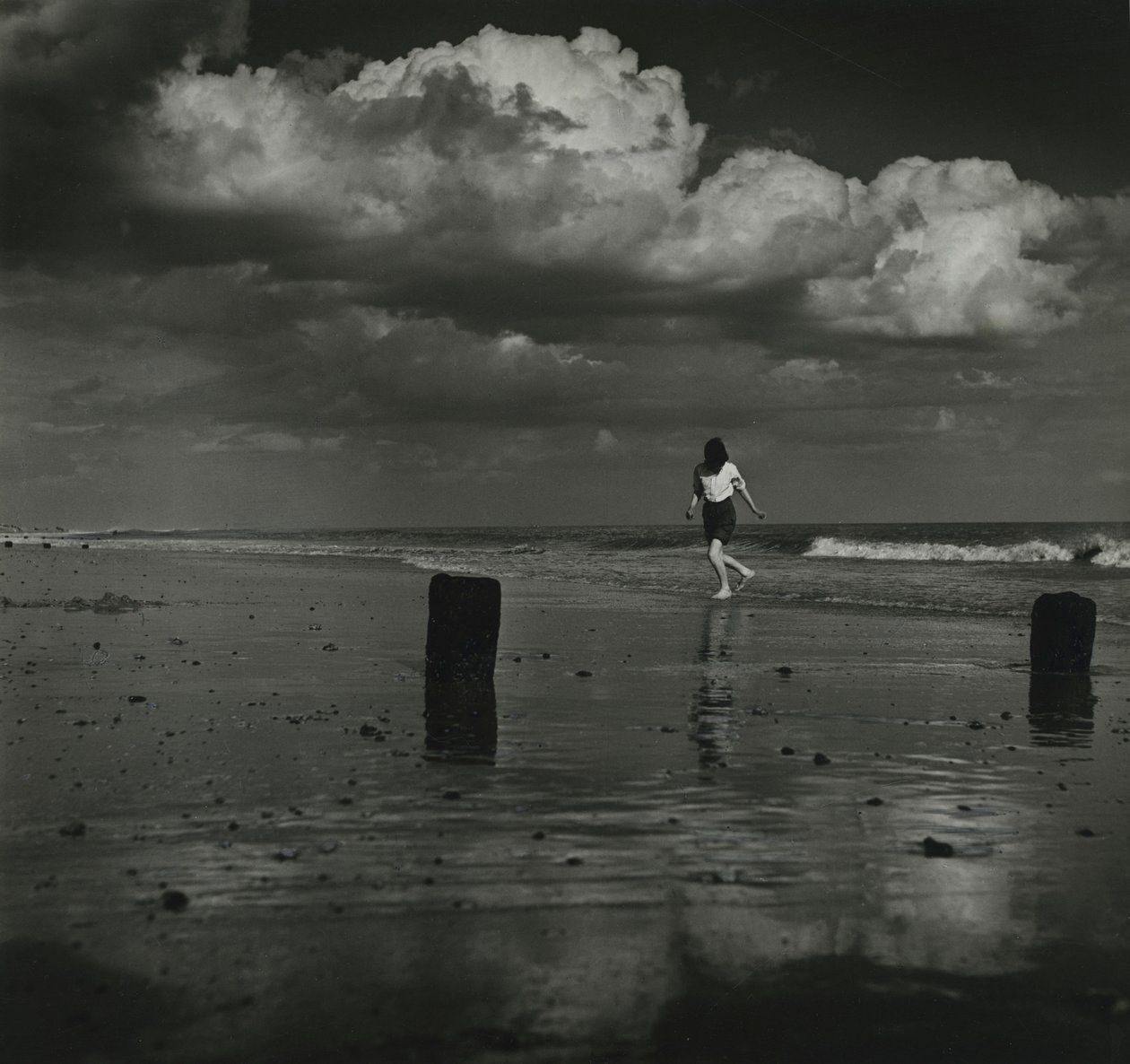 Criança a brincar com as ondas na praia. de Godfrey Macdominic