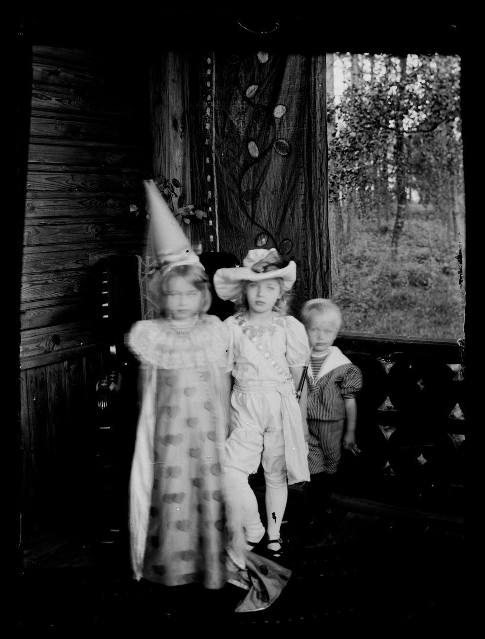 Crianças fantasiadas no alpendre da casa dos Andersins, as crianças Gadd e Karin e Lisa Anders de Hugo Simberg