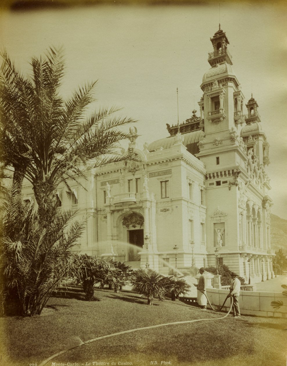 O teatro anexo ao Casino em Montecarlo. Em primeiro plano, uma vista do jardim enfeitada com palmeiras. de Italian Photographer