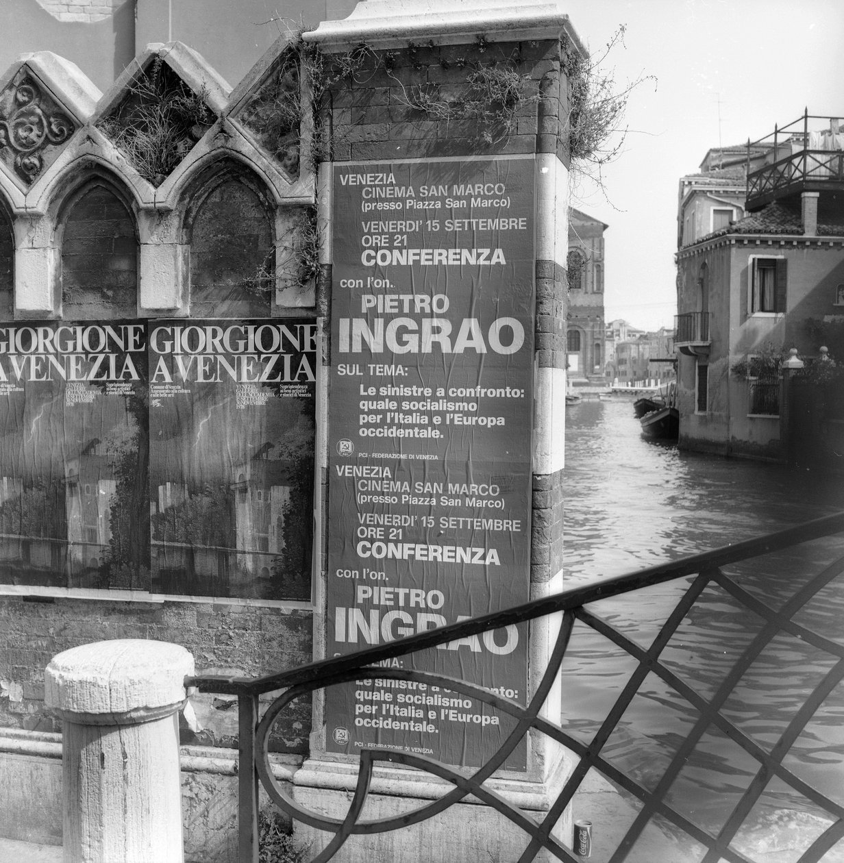 Vista de um canal em Veneza com cartazes anunciando uma exposição de Giorgione e um manifesto político em primeiro plano de Italian Photographer
