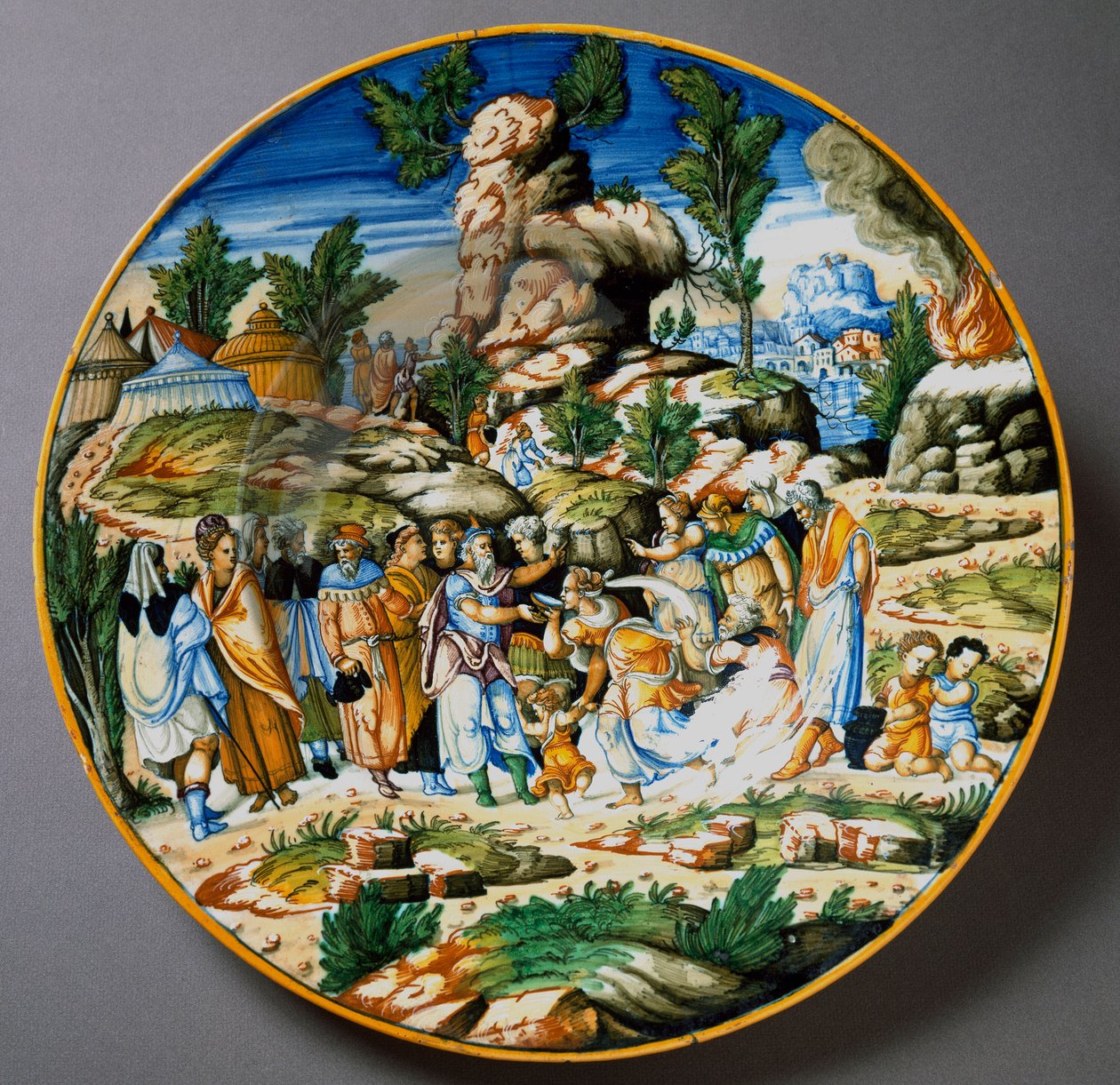 Moisés levanta água da rocha e dá uma bebida ao povo de Israel Placa cerâmica produzida em Urbino, na oficina Fontana, Itália. 1560 aproximadamente Florença, Museo Nazionale del Bargello de Italian School