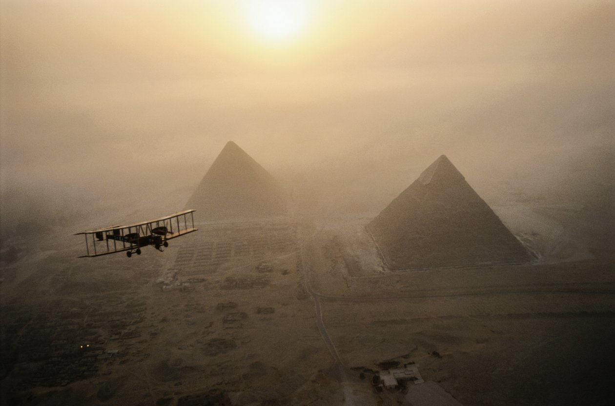 O avião Vimy voa sobre as pirâmides envoltas em nevoeiro durante um dia de sol dourado... de James L Stanfield