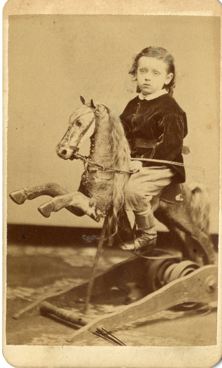 Rapazinho com chicote no cavalo de balanço de John McCaffrey