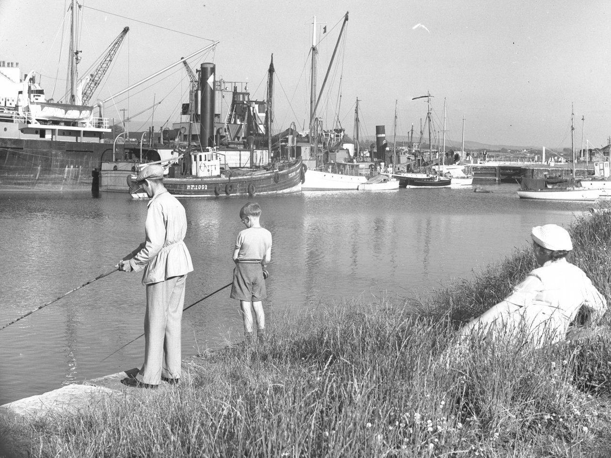 Um homem e um rapaz a pescar na doca de Glasson enquanto uma senhora marinha; paisagem marítima; ted atrás olha, vários barcos atracados de Joseph Hardman