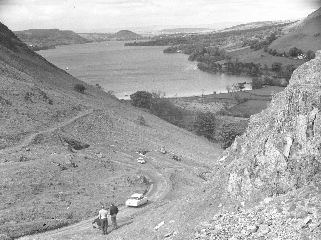 Vista de uma encosta com estrada, carros e pessoas, lago ao fundo de Joseph Hardman