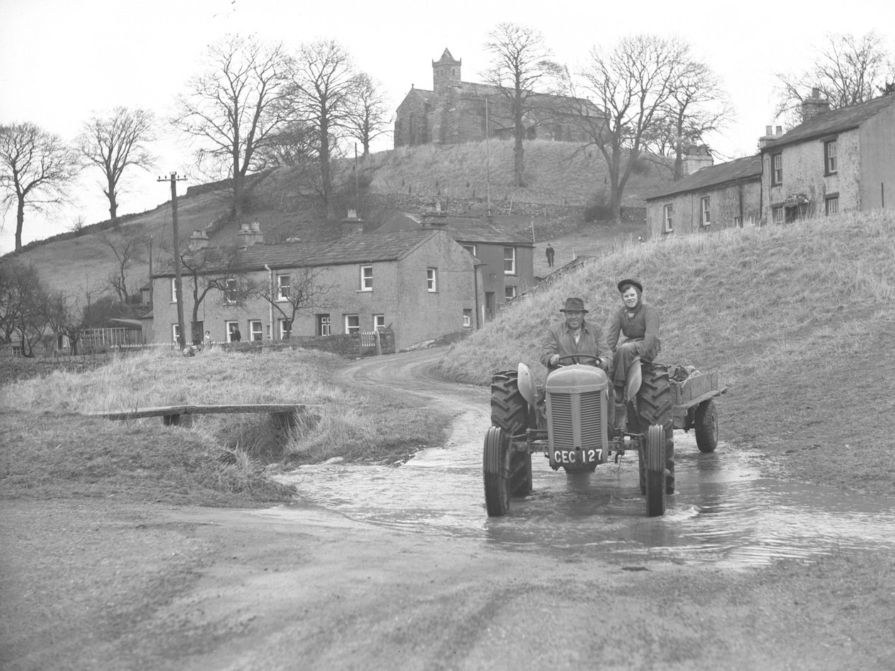 Homem e mulher conduzindo um trator que desce a estrada através de um vau em Crosby Garret de Joseph Hardman
