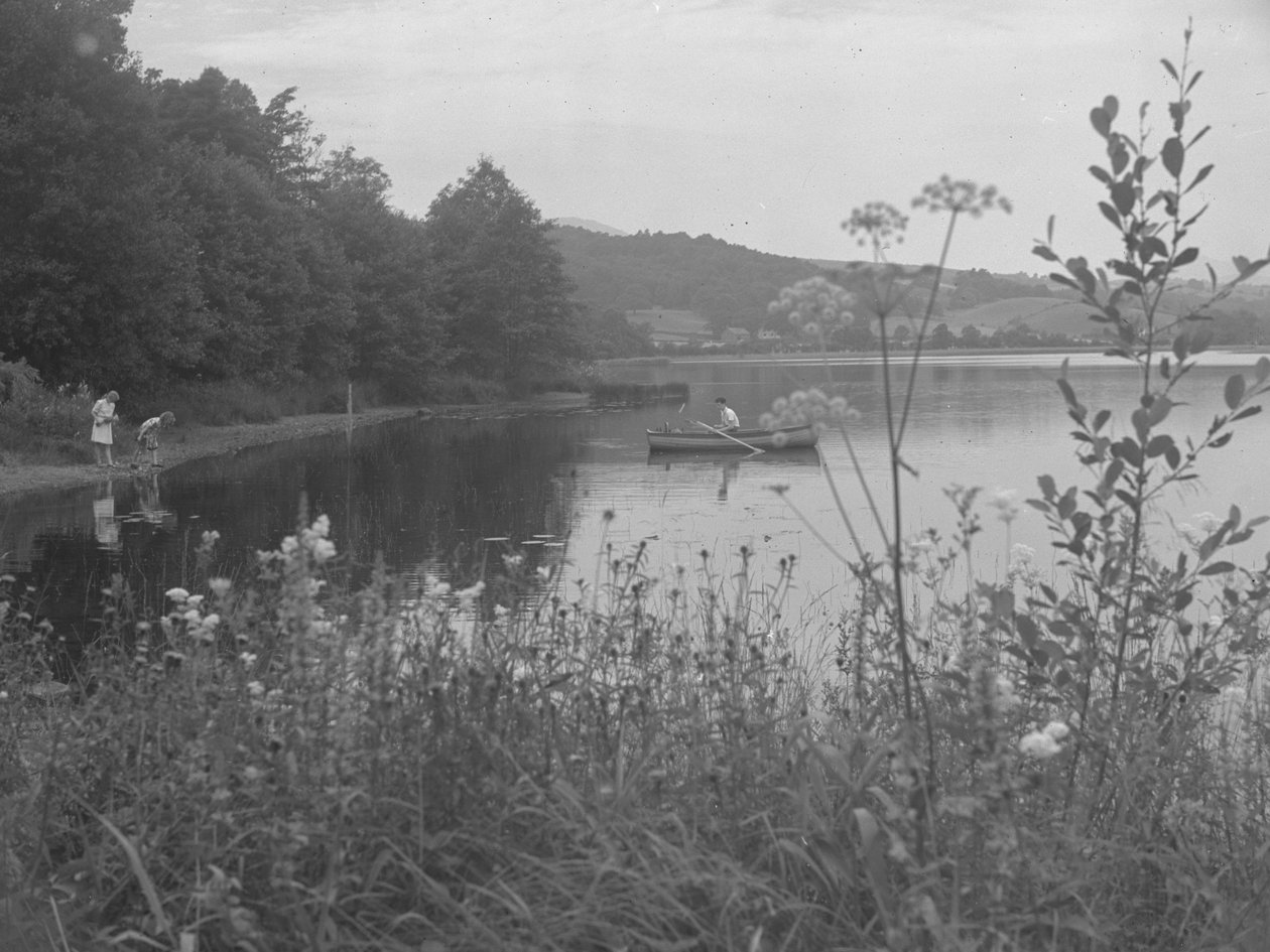 Homem a pescar num barco em Estwaite Water e duas raparigas à beira da água de Joseph Hardman