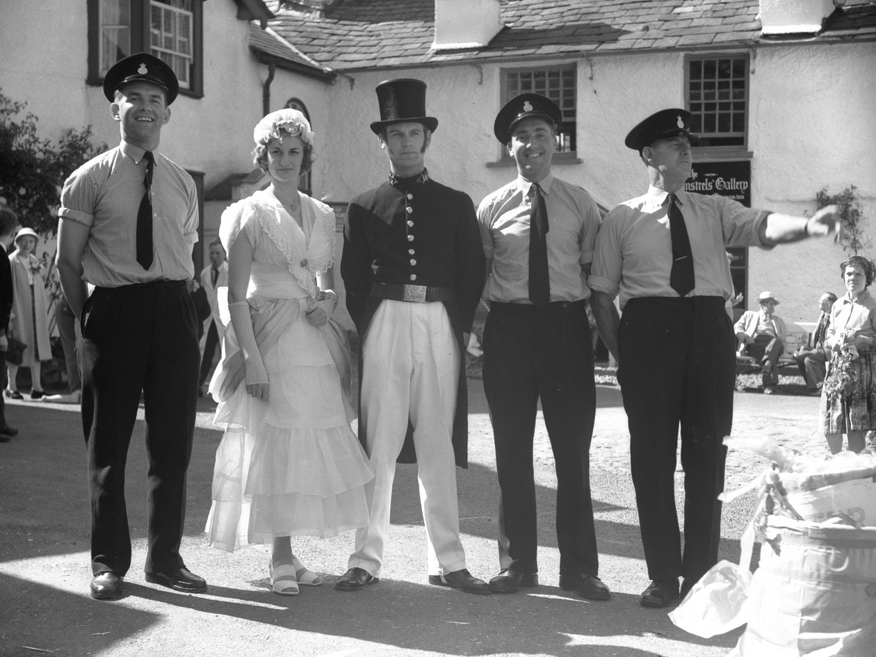 Homens e mulheres vestidos a rigor na Hawkshead Fayre, em frente ao Mintrel