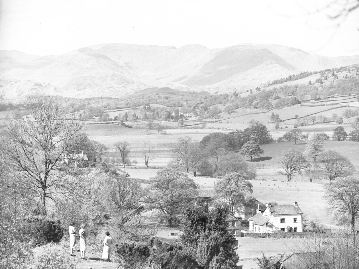 Três mulheres de pé a olhar para um lago em Esthwaite, com as montanhas ao fundo de Joseph Hardman